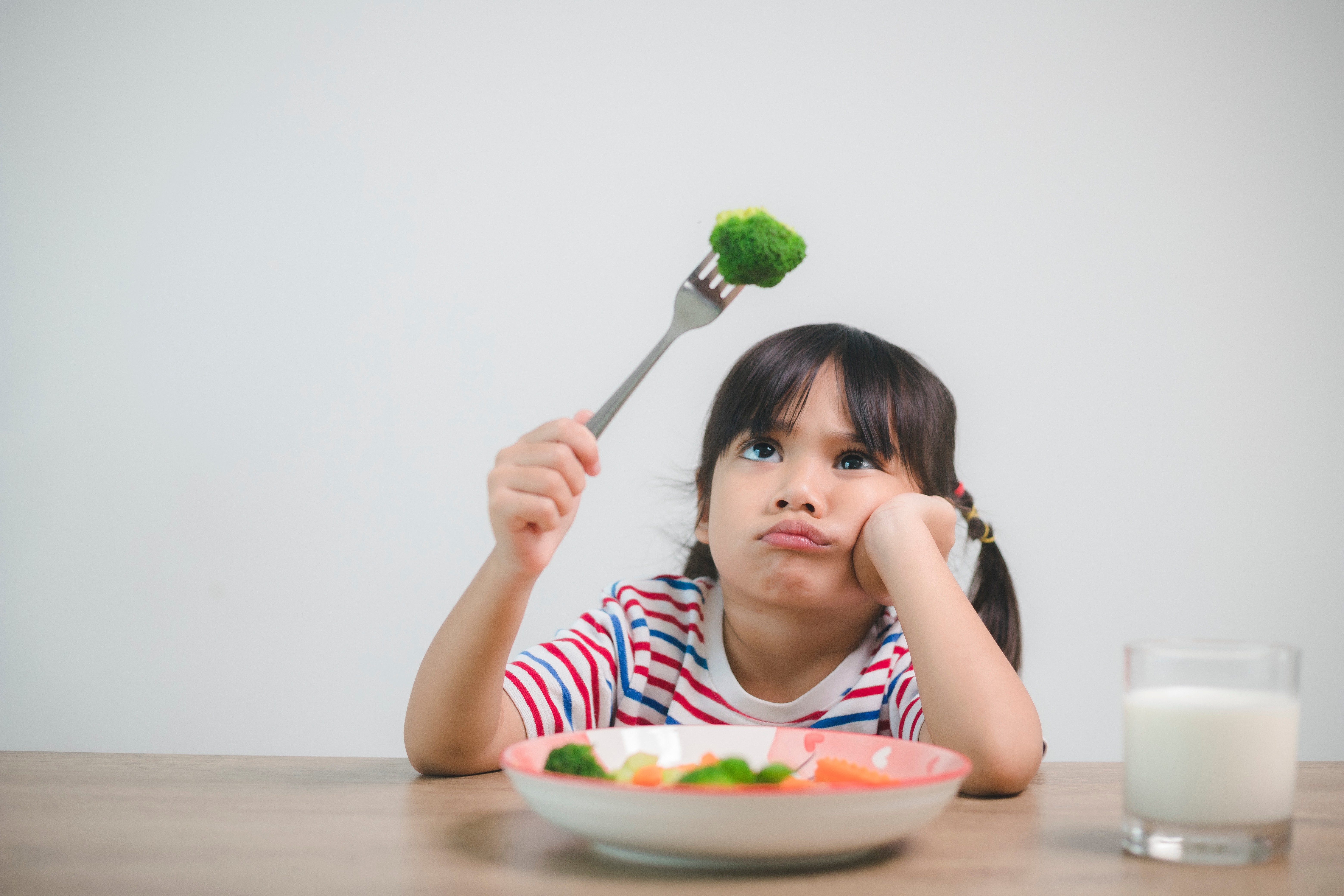 Ausgewogene Ernährung bei Kindern - Mädchen lustlos mit Broccoli