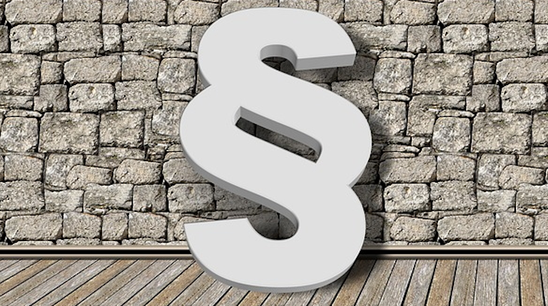 Paragraphensymbol vor Pflastersteinmauer